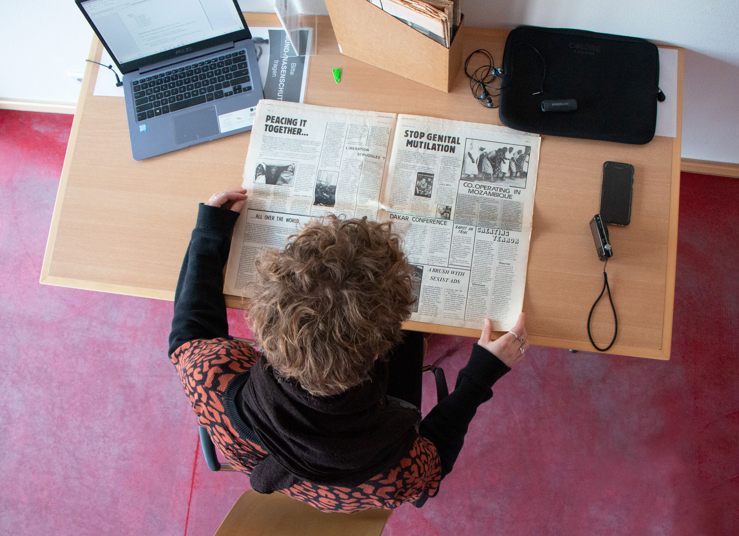 Rückenansicht einer Besucherin bei der Arbeit an einem Tisch im Lesesaal