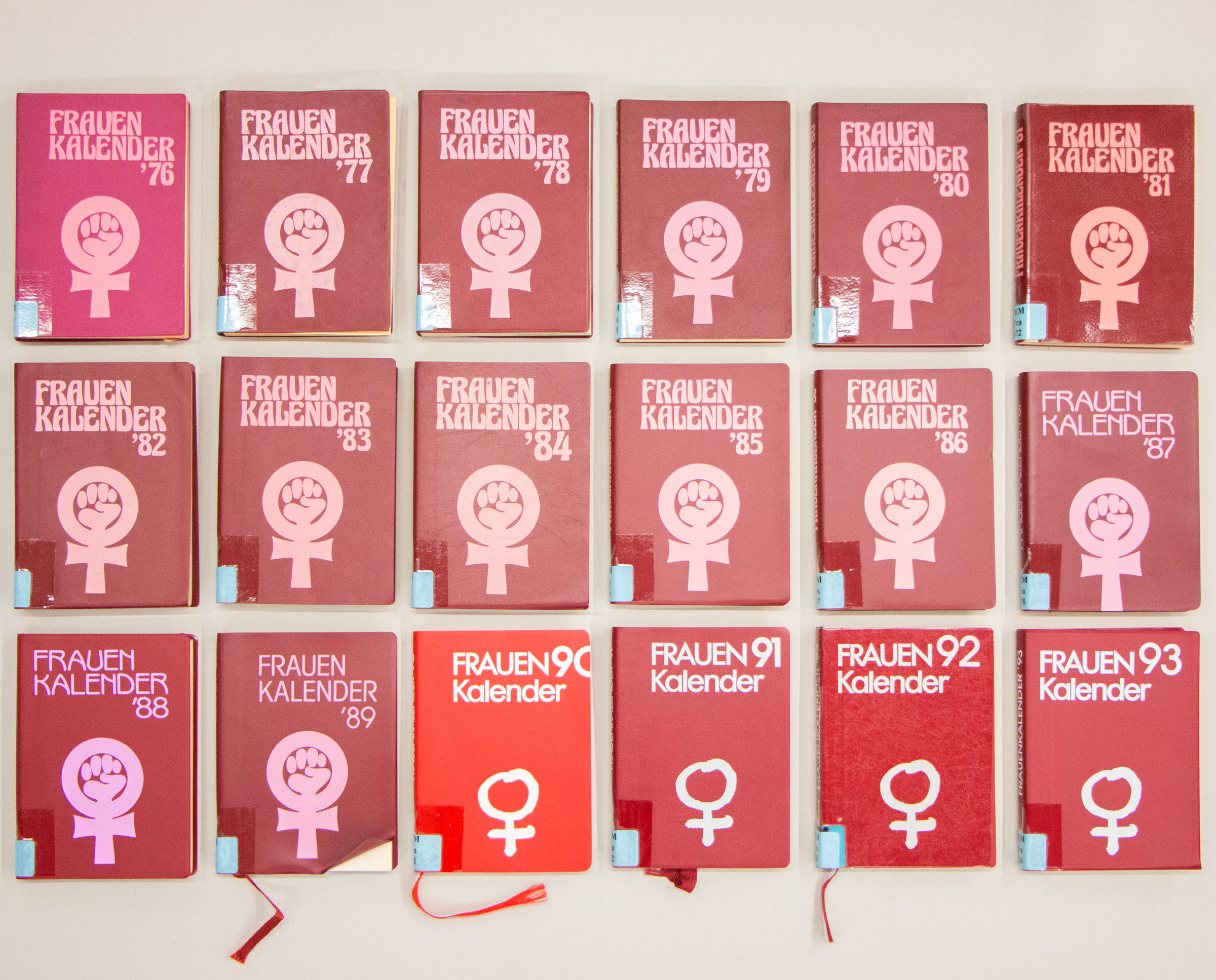 sechszehn neben und übereinander angeordnete rote Frauenkalender in drei Reihen zeigen Frauenzeichen mit und ohne geballte Faust auf Cover