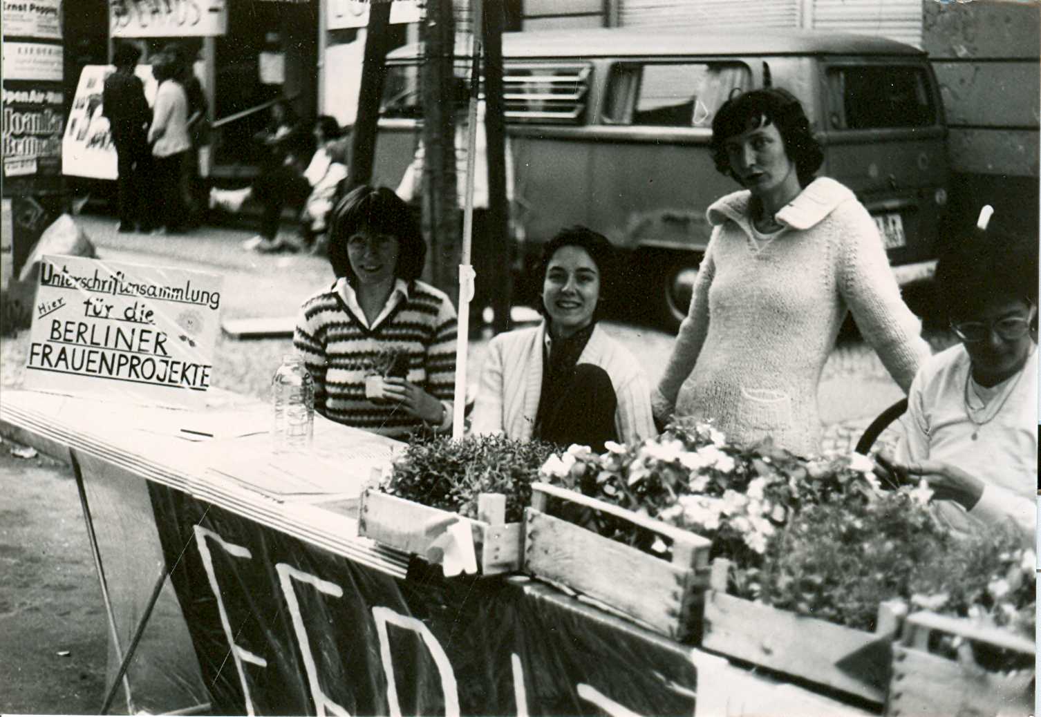 Ursula Nienhaus (links) und drei weitere Mitarbeiterinnen hinter einem Informationsstand des FFBIZ. Auf dem Info-Tisch stehen Kästen mit Blumen und liegen Listen zur Unterschriftensammlung für die Berliner Frauenprojekte aus